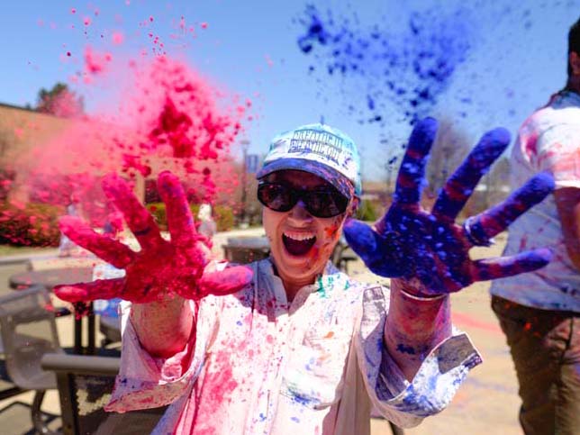 A Penn State Scranton student shows off her multi-colored hands and attire after participating in the Hindu holiday of Holi, the Festival of Colors.