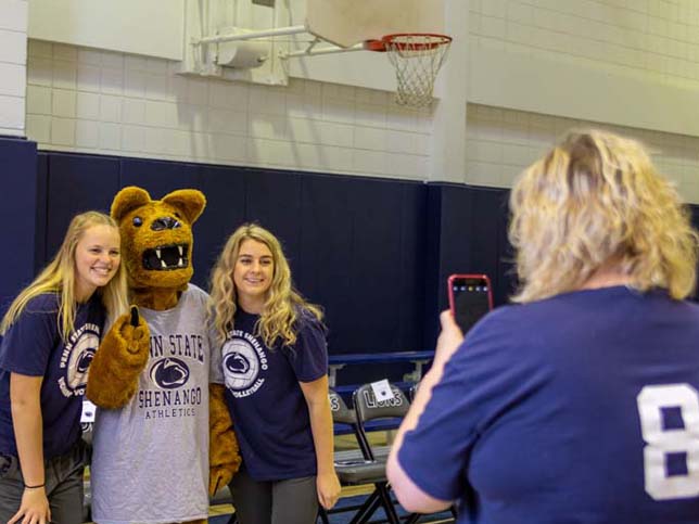 Two members of the Penn State Shenango women’s volleyball team have their photo taken with the Nittany Lion Mascot at Buhl Club’s gymnasium.