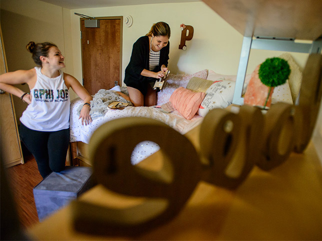 two students laughing as the unpack in their new dorm room