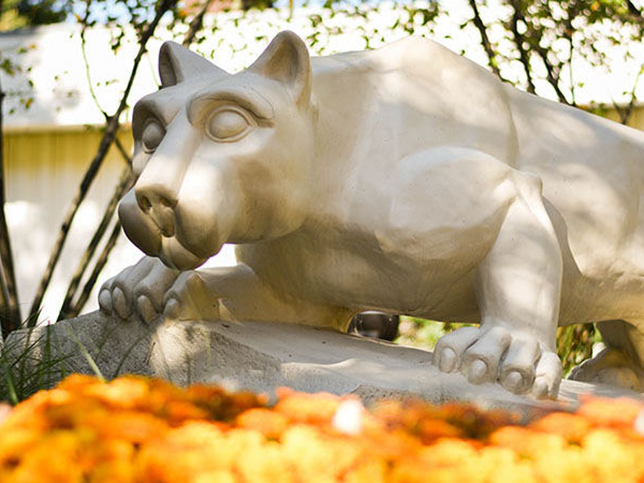 In the foreground are some golden, yellow, and orange mums, surrounding the Nittany Lion Shrine.